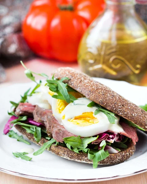 Panino con bistecca di manzo alla griglia, uova, rucola, pane di segale — Foto Stock