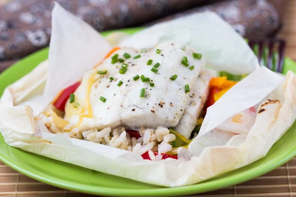 White fish fillet baked in paper, parchment with rice, pepper — Stock Photo, Image
