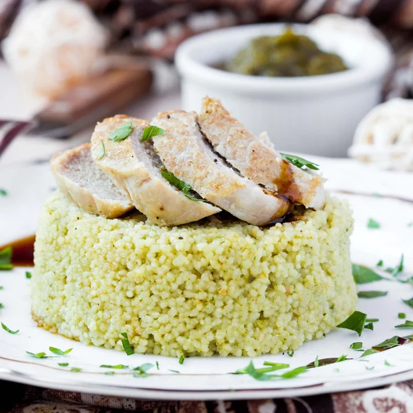 Couscous met pestosaus, gebakken varkensvlees, smakelijke schotel gesneden — Stockfoto