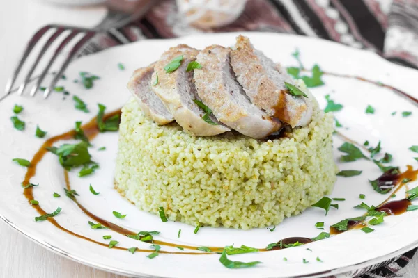 Couscous dengan saus pesto, daging babi goreng, hidangan lezat — Stok Foto