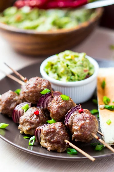 Meat kebab, beef balls on skewer with onions, sauce guacamole — Stock Photo, Image