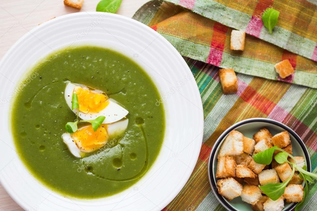 Green spring, summer healthy cream soup with herbs, egg, crouton
