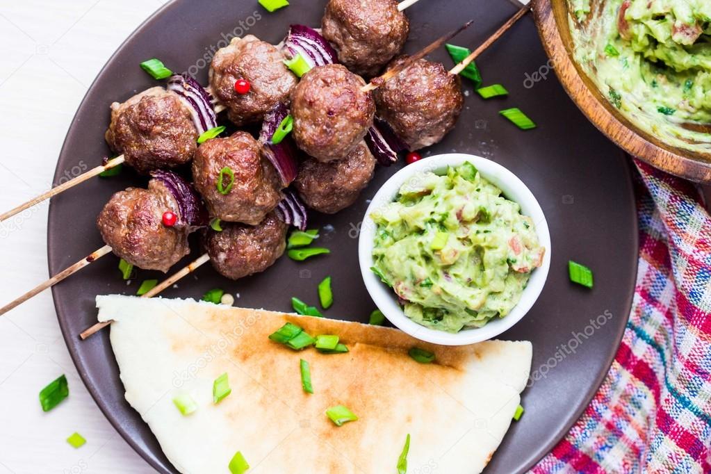 Meat kebab, beef balls on skewer with onions, sauce guacamole