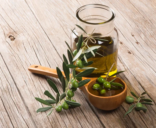 Frasco con aceite de oliva y rama de aceitunas verdes —  Fotos de Stock