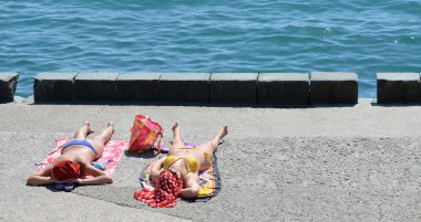 Deniz kenarında güneşlenirken bikinili iki kız