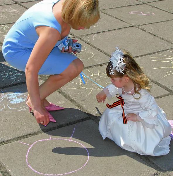 9 maggio. Il giorno della vittoria. Donna e ragazza con il nastro di San Giorgio disegnare con gesso su asfalto — Foto Stock