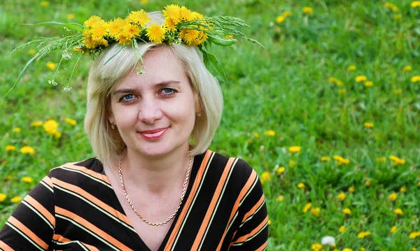 De vrouw ligt op het gras met een krans van bloemen op haar hoofd — Stockfoto
