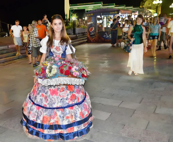 Menina bonita em vestido de noite, vendendo flores no passeio noturno de Yalta Imagens Royalty-Free