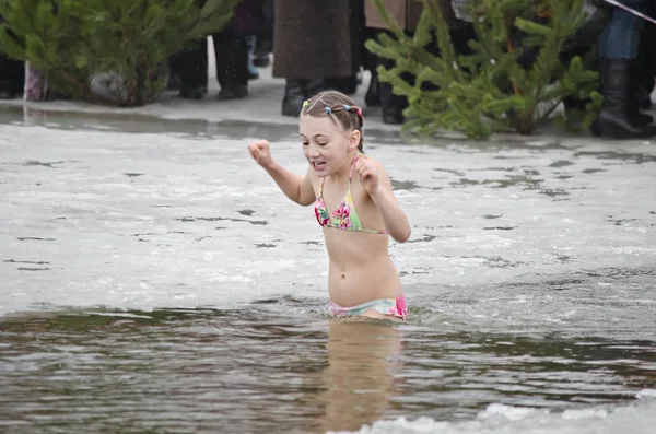 A criança banha-se no rio no inverno. Férias religiosas da Epifania Fotografia De Stock