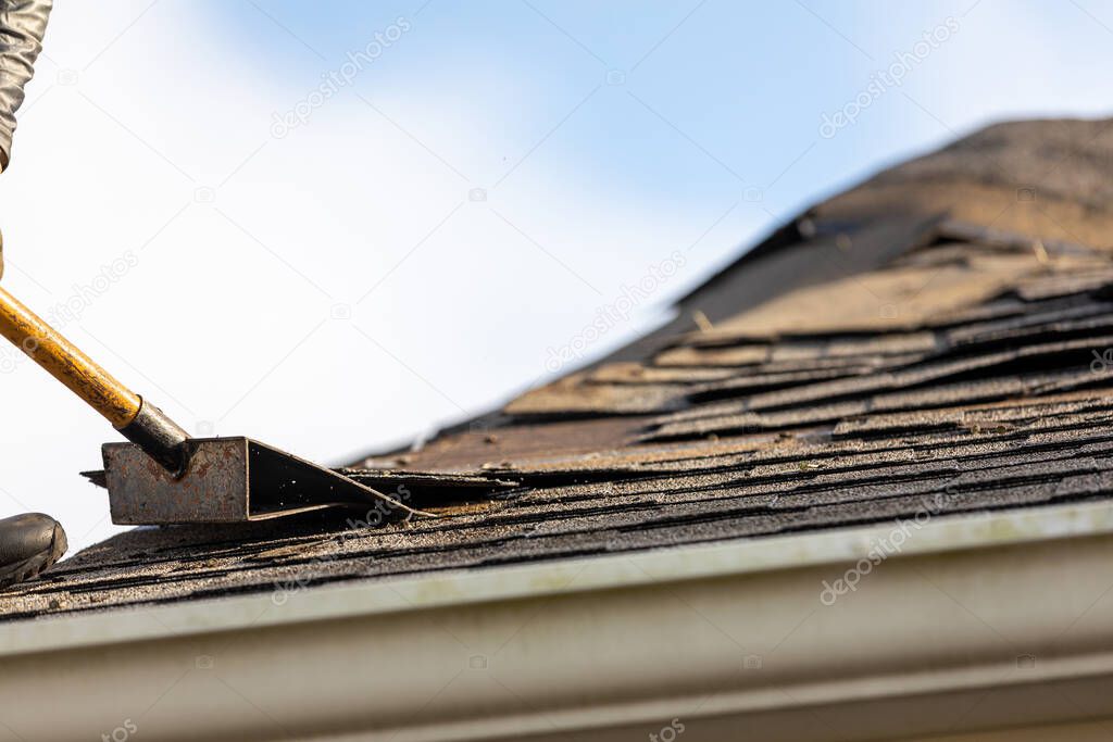 roofer removing roof shingles with roof shingle remover