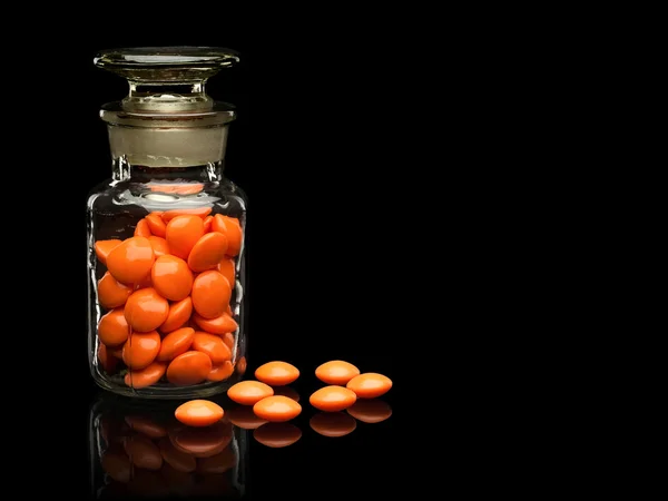 Glass vial with a glass cover and pills of orange colors. — Stock Photo, Image