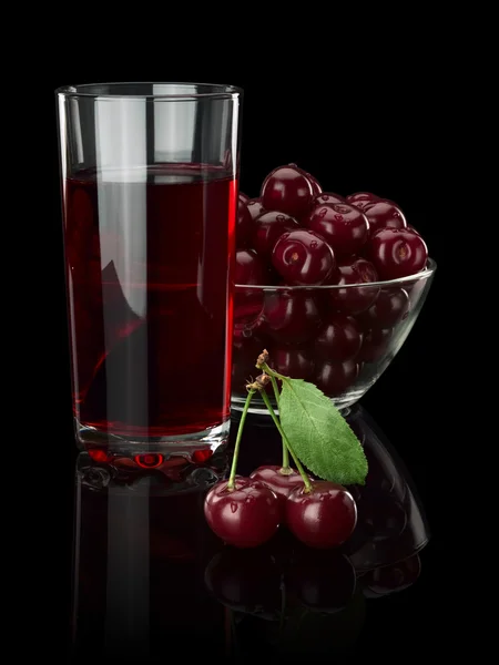 Bagas de uma cereja e suco em um fundo preto . — Fotografia de Stock