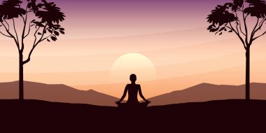 Yogada arabuluculuk yapan kişi, gün batımında büyük ağaçlar ve dağ manzaralı güzel bir manzara üzerinde poz verir.