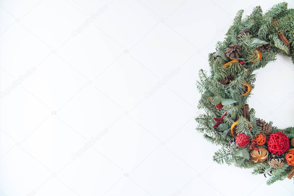 Wreath made of natural fir branches hanging with natural ornaments: bumps, cones, garlands, stars. Christmas Holiday Wreath Isolated On White Background.