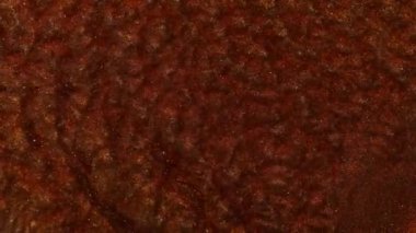 Bakır, demir ve pas renginde sıvı. Sudaki parlak pigmentler dalgalarda titreşir. Soyut bronz rengini nehrin rengine boyardı. Makro görüntüyü kapat. Mürekkep suyun altında dönüyor..