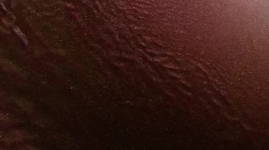 Soyut sıvı sanat arka planı, metalik parlak pembe su, büyülü parıltı nehri ya da şarap renkli fantezi okyanus dalgaları. Parlak ve yanardöner inci parçacıklarının hareketinin makro videosu