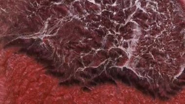 Grunge arkaplan sıvısı, parlak alkol mürekkebi ile soyutlanmış kırmızı su, nehir akışı, köpüklü şarap rengi okyanus dalgaları. Kırmızı ve gümüş boyanın makro videosu. Şaşırtıcı.