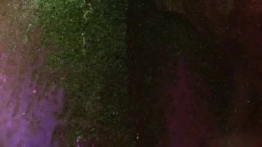 Soyut grunge sıvı sanat arka planı. Mor sıvıda altın kum taneciklerinin hareketi. Parlak koyu mor bir boyanın akışı, uzayın çöküşü. Yüksek kaliteli boya akışı videosu.