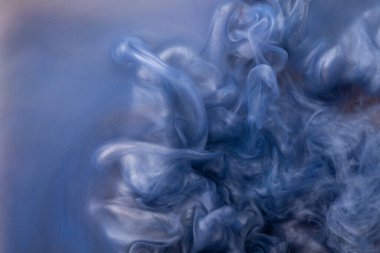 Suya gerçek boya damlaları düşer. Mavi arkaplanda soyut mavi mürekkep bulutu çarpışması izole edildi. Sıvı mermer deseni. Modern sanat. Soyut akrilik resim.