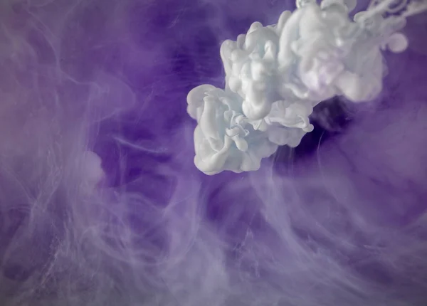 Real shot color paint drops in water. Abstract white Ink cloud collision isolated on violet background. Liquid marble pattern. Modern art. Abstract fluid acrylic painting.