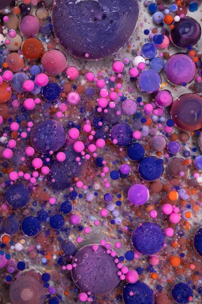 Purple, blue, pink and yellow liquids mix. Creative multicolor background. Acrylic paint balls abstract texture. Bright colors fluid, flowing wallpaper design. Mixed pigments violet backdrop.