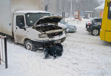 Arabanın sürücüsü karda yalan onarır.