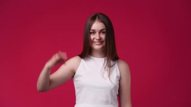 Kırmızı arkaplanda iyi işareti gösteren tatmin olmuş bir kadının 4k videosu. Onay kavramı.