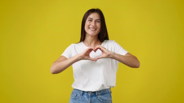 Video Smiling Female Showing Heart Shape Isolated Yellow Background Concept — Stock Video