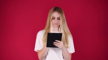 4K video 'da konsantre bir kadın kırmızı arka planda izole edilmiş bir şey yazıyor. Yazma kavramı,