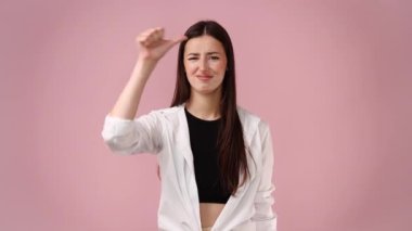 Memnuniyetsiz kadın onay vermiyor, pembe arka planda baş parmağı kapalı tutuyor. Vücut dili kavramı.