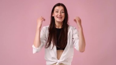 Pembe arka planda dans eden heyecanlı genç bir kadının 4K videosu..