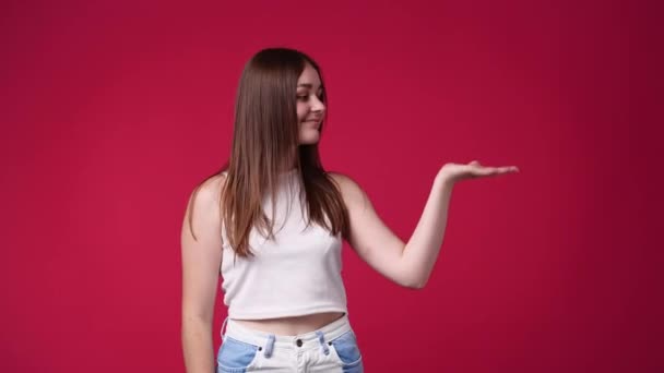 Video Einer Jungen Frau Die Etwas Auf Rotem Hintergrund Präsentiert — Stockvideo