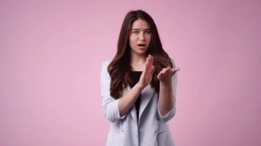 4k video of woman rubbing her hands together on pink background. Concept of relax emotion.