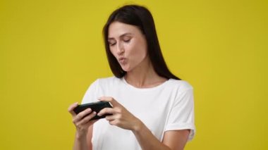 Kadının sarı arka planda telefonundan bir şey izlediği 4K videosu. Teknoloji kavramı.