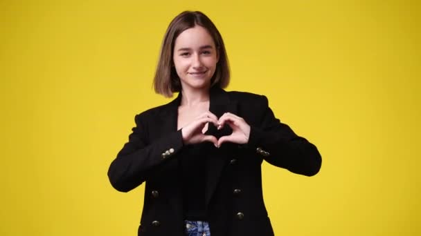 Video Hymyilevä Nainen Osoittaa Sydämen Muodon Eristetty Keltaisella Taustalla Rakkauden — kuvapankkivideo