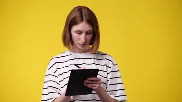 Vídeo Mulher Concentrada Escrevendo Algo Isolado Sobre Fundo Amarelo Conceito — Vídeo de Stock
