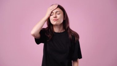 Pembe arka plan üzerinde düşünen ve yan bakan genç bir kadının 4k videosu..