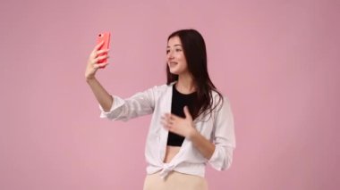Pembe arka planda selfie çeken kadın videosu. Etkilenenlerin konsepti.