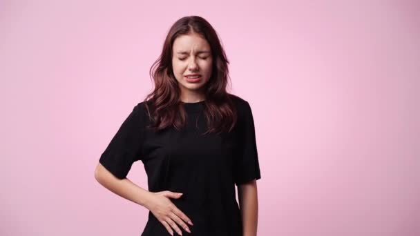 4K视频中的心烦意乱的女人 她的胃被粉色背景隔离 负面情绪概念 — 图库视频影像