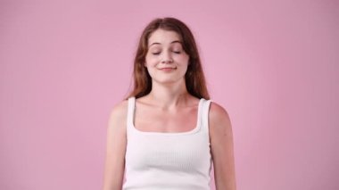 Pembe arka planda ellerini sallayan bir kadının 4K videosu. Rahatlama duygusu kavramı.