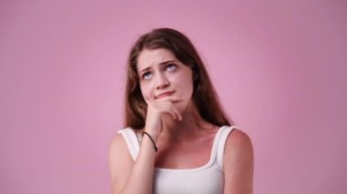 Pembe arka planda düşünen güzel bir kızın 4K videosu. Duygu kavramı.