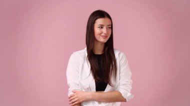 Pembe arka plan üzerinde düşünen ve yan bakan genç bir kadının 4k videosu..