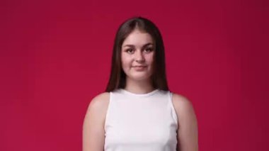 Kırmızı arka planda sırıtan sevimli beyaz bir kadının 4k mahsul videosu. Sevimlilik kavramı.