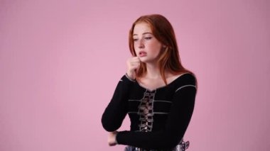 Pembe arka planda düşünen ve aşağıya bakan genç bir kadının 4K videosu. Düşünce kavramı.