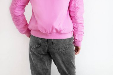 Beyaz tişörtlü, pembe ceketli gri kotlu beyaz kadın. Arkadan bak. Beyaz arkaplan.