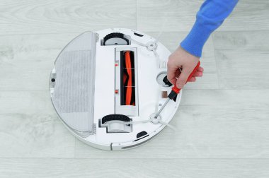 Beyaz kadın, robot bir elektrikli süpürgeye tornavidayla fırça ekliyor..