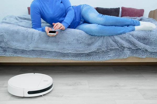 스마트폰으로 청소기를 제어하는 침대에 — 스톡 사진