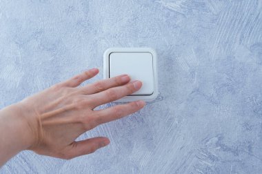 Kafkasyalı bir kadının eli odadaki düğmeyi açıyor..
