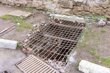 Paslı ızgara ızgarası. Feodosia 'da yolun kenarında kırık bir kanalizasyon.