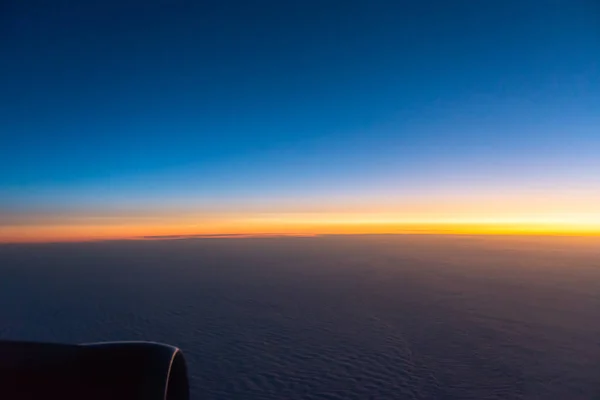 飛行機の窓からの日の出 地平線は太陽のオレンジ色の光によって着色されています 昇る太陽の最初の光線 — ストック写真